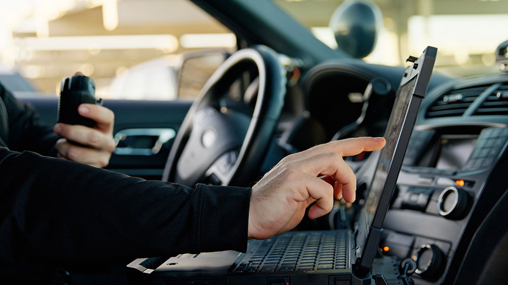 Officer using a laptop inside a patrol vehicle